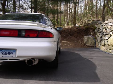 1996 Ford Probe - Rear view of a white 1996 Ford Probe parked outdoors with a stone wall and trees in the background.