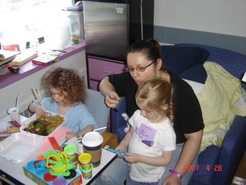1993 Ford Bronco - A woman and two children are eating takeout food at a table with toys and drinks.