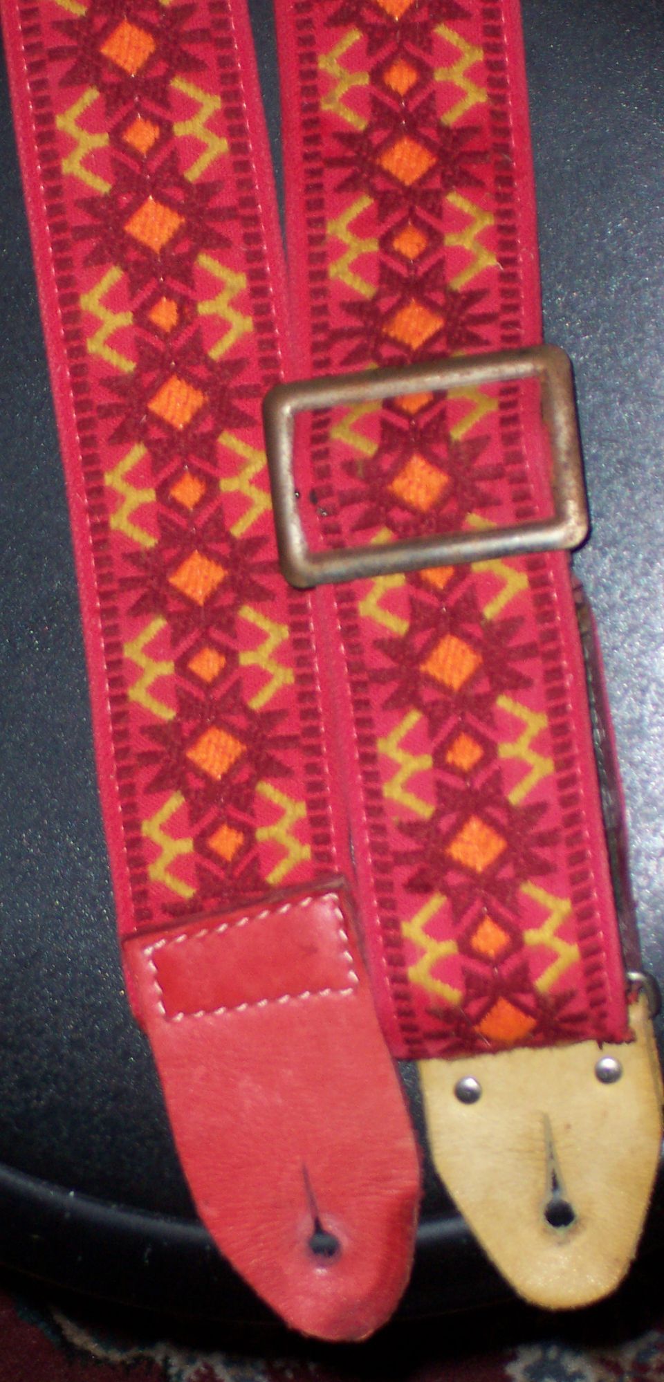 Vintage red and orange woven guitar strap with leather ends and brass buckle