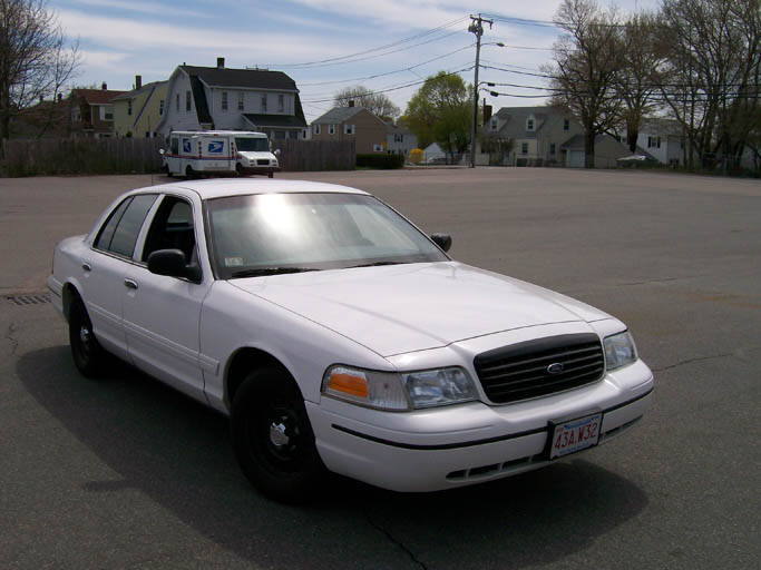White Ford Crown Victoria sedan, three-quarter front view in a parking lot