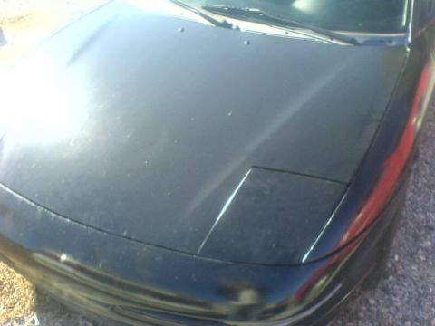 1996 Ford Probe - A dark-colored car's hood and front corner are visible, with a pop-up headlight in the closed position.