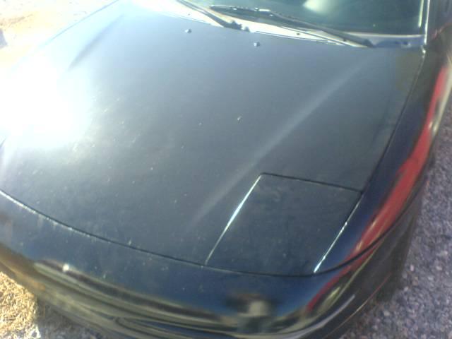 Black car hood with a closed pop-up headlight, viewed from a high angle