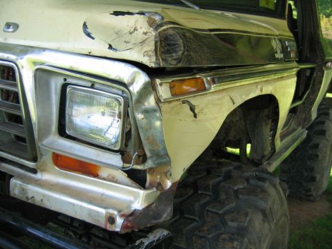 1992 Ford Mustang - The front end of a pickup truck shows significant damage to the fender and hood, with large off-road tires mounted.