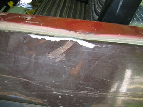 1992 Ford Mustang - The side of a red 1992 Ford Mustang shows significant wear and tear, with chipped paint and scratches.