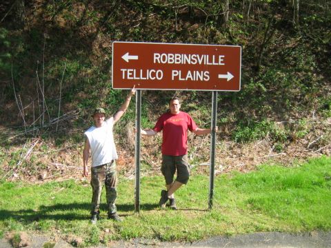1992 Ford Mustang - Two men pose for a photo next to a directional road sign in a wooded area.