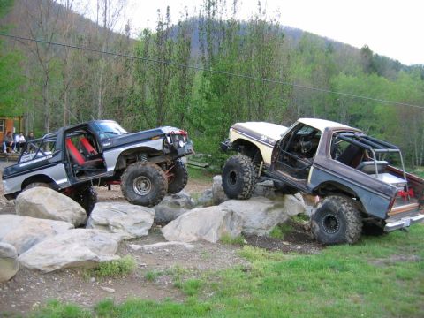 1992 Ford Mustang - Two off-road trucks are shown traversing a challenging rocky landscape.