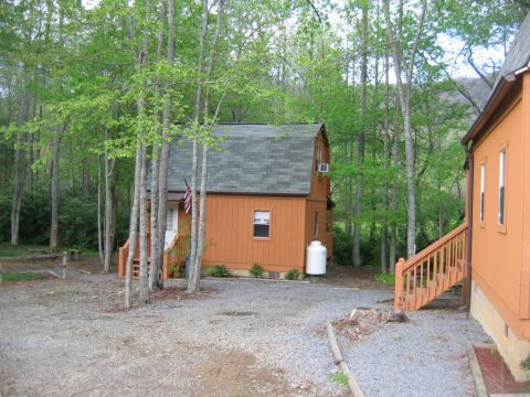 1992 Ford Mustang - A rustic scene shows an orange cabin with a propane tank and wooden stairs amidst a wooded area.