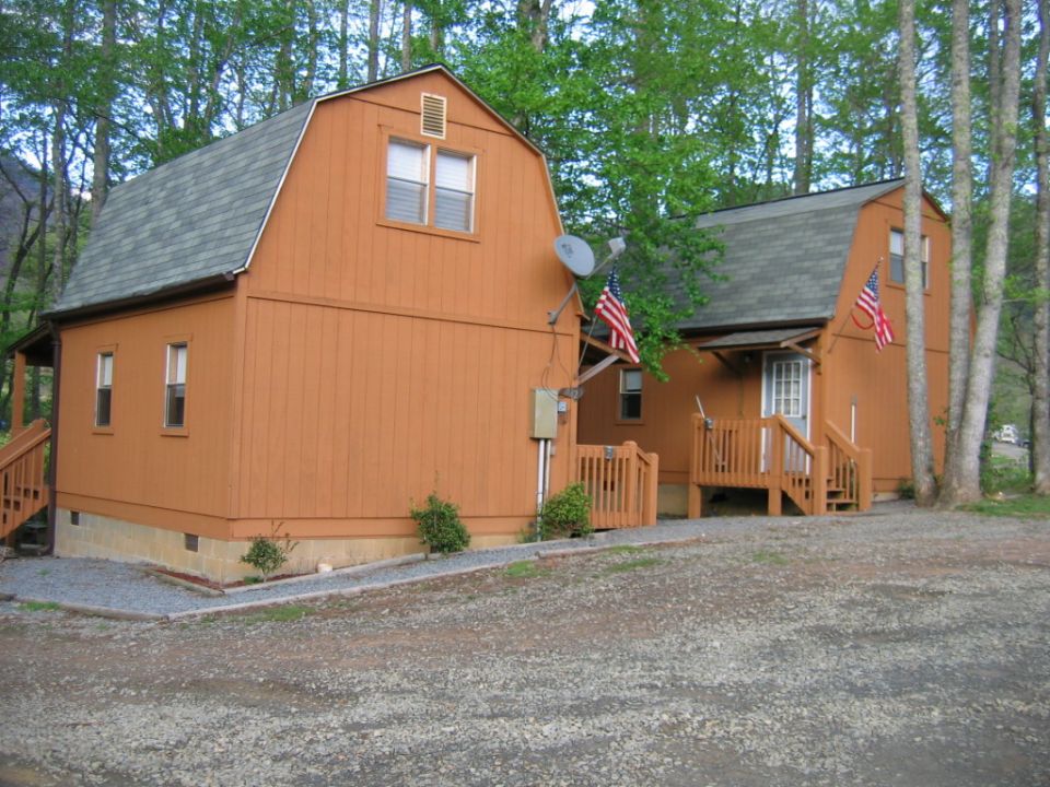 Two orange cabins with gambrel roofs and American flags