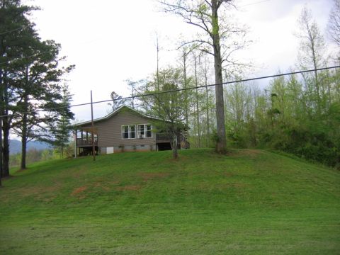 1992 Ford Mustang - A house is situated on a hill surrounded by trees and grass.
