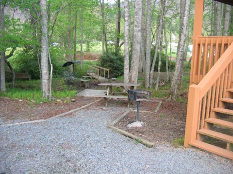 1992 Ford Mustang - This outdoor scene features a picnic table and grill surrounded by trees, with wooden stairs visible on the right.
