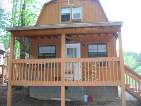 1992 Ford Mustang - A wooden cabin with a porch and stairs is shown in a wooded area.
