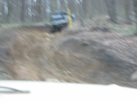 1992 Ford Mustang - A vehicle navigates a challenging off-road trail through a forest.