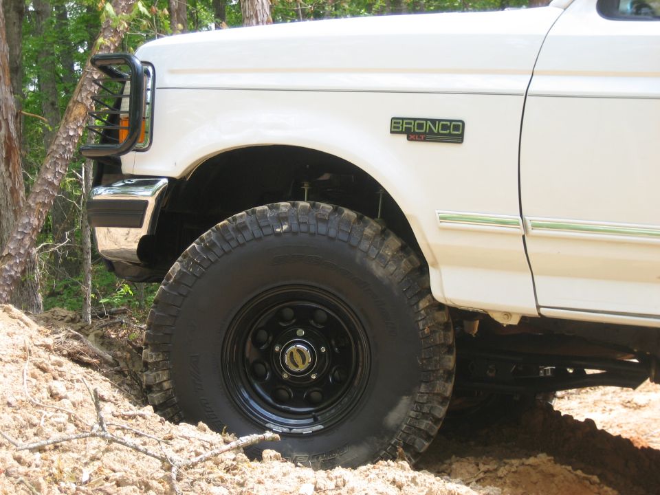 White Ford Bronco XLT front fender and BFGoodrich mud tire on black steel wheel on a dirt bank