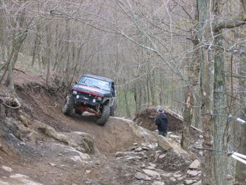 1992 Ford Mustang - An off-road vehicle tackles a challenging, wooded trail, demonstrating its capabilities on rough terrain.