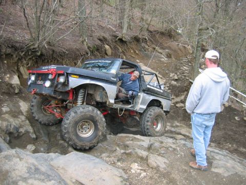 1992 Ford Mustang - Off-road vehicle tackling a challenging rocky path with a spectator watching.