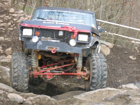 1992 Ford Mustang - An off-road vehicle with prominent suspension and large tires is shown tackling a challenging rocky obstacle.