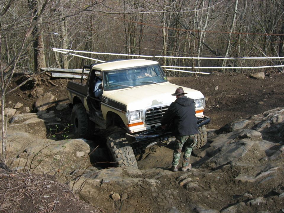 Tan pickup truck with black trim and large off-road tires navigating a rocky trail