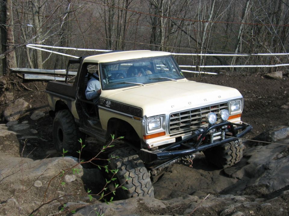 Cream 1979 Ford F-150 pickup truck with off-road tires and winch navigating rocks