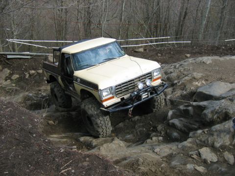 1992 Ford Mustang - Modified pickup truck tackles a challenging off-road course with steep inclines and large boulders.