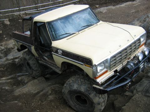 1992 Ford Mustang - Modified pickup truck with oversized tires and off-road bumper tackling a challenging rocky path.
