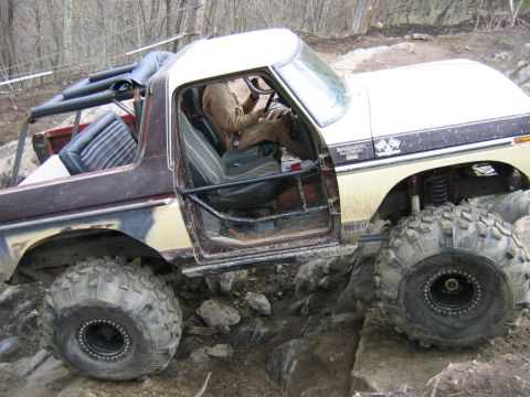 1992 Ford Mustang - This heavily modified Ford Bronco is shown off-roading over rocks. The "BRONCO" and "4x4" badges are visible on the fender.