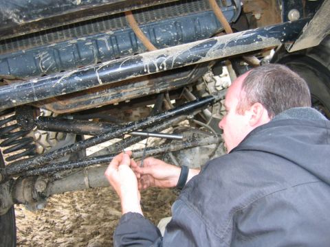 1992 Ford Mustang - A man is working on the suspension system of a vehicle, possibly making repairs or adjustments.
