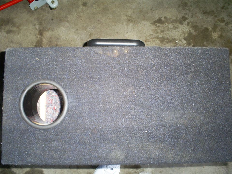 Black speaker enclosure with a circular opening on the left and a handle on top