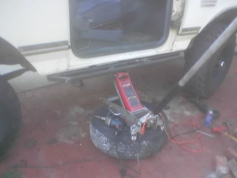 1989 Ford Bronco - A vehicle is being serviced with a jack and tools on the ground.