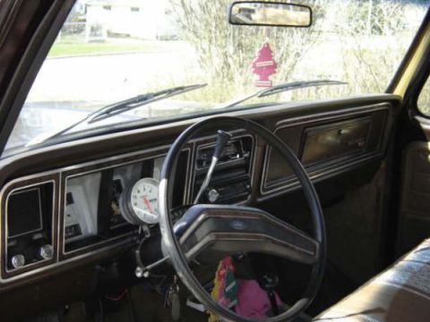 1979 Ford Bronco - The dashboard of an older truck features an aftermarket tachometer and a classic pine tree air freshener.
