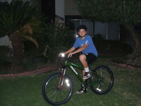1988 Ford Bronco - A young boy wearing a helmet rides a green Specialized bicycle at dusk, with the front light illuminated.
