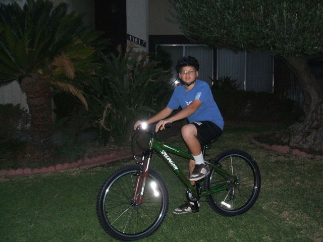Young rider on a green Specialized mountain bike on a lawn at night