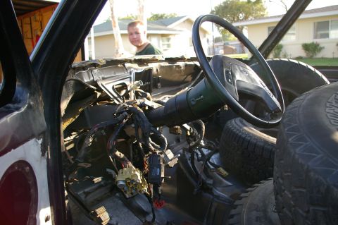 1986 Ford Bronco - The interior of a vehicle is shown with its dashboard removed, revealing wiring and spare tires.