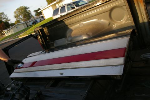 1986 Ford Bronco - Tailgate with red and silver stripes is open, revealing the interior of a vehicle.