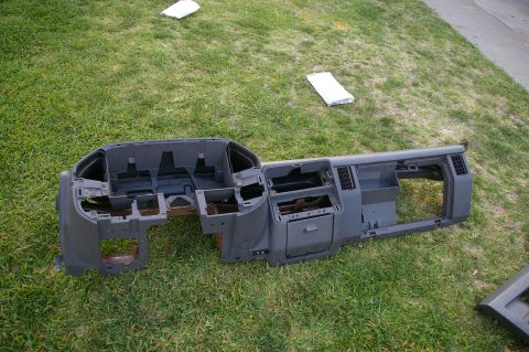 1986 Ford Bronco - Dashboard assembly removed from a vehicle and placed on the grass.