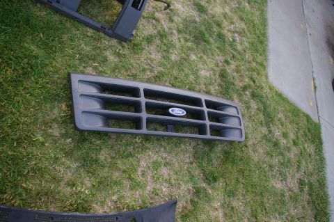 1986 Ford Bronco - A Ford grille with the blue oval emblem is shown resting on a grassy area.