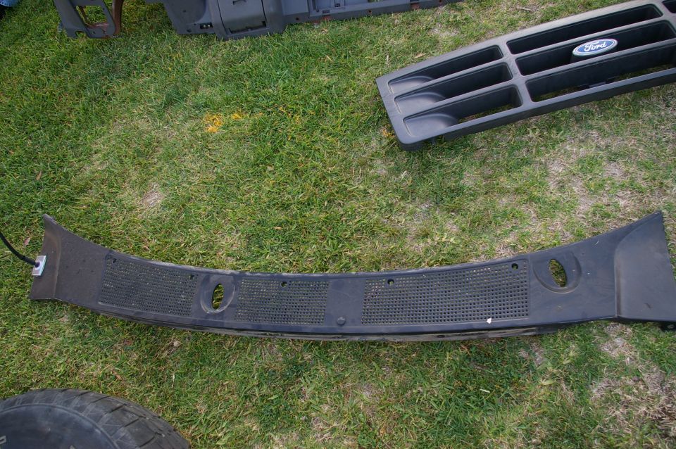 Black Ford grille with oval emblem and black dashboard trim piece on grass