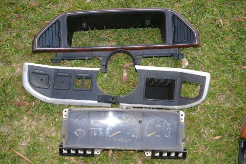 1986 Ford Bronco - Dashboard components, including trim pieces and a gauge cluster, are displayed on a grassy surface.