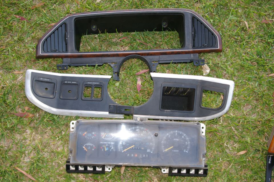 Dashboard trim and instrument cluster laid out on grass