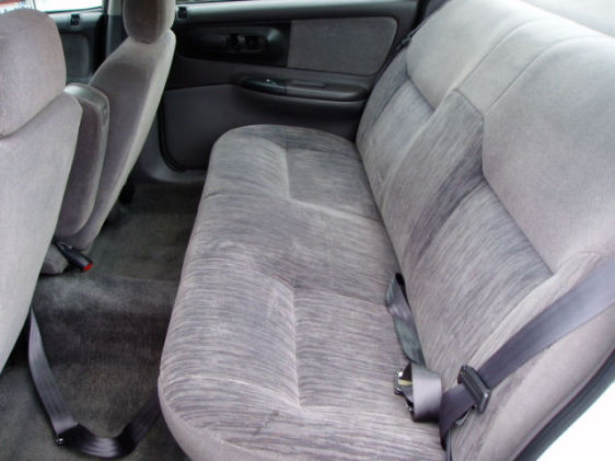 Gray cloth rear bench seat in a sedan with seatbelts and carpeted floor