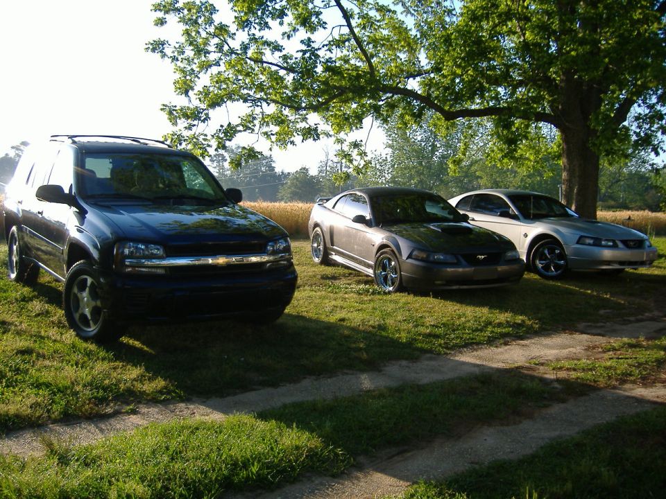 2003 Ford Mustang parked next to a silver Mustang and a black SUV