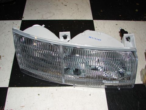 1992 Ford Taurus - This headlight assembly features a clear lens and a ribbed interior, likely for a vehicle from the early 1990s.