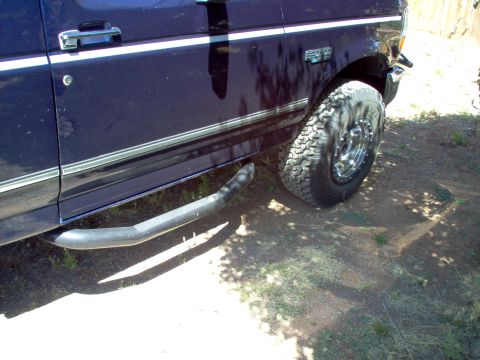 1995 Ford Bronco - The side of a 1995 Ford Bronco is shown with a large off-road tire and running boards.