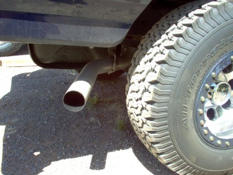 1995 Ford Bronco - Close-up view of the exhaust pipe and a tire on a dark blue vehicle.