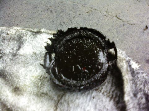 1995 Ford Bronco - A close-up view of a damaged cap covered in dark oil, resting on a white rag.