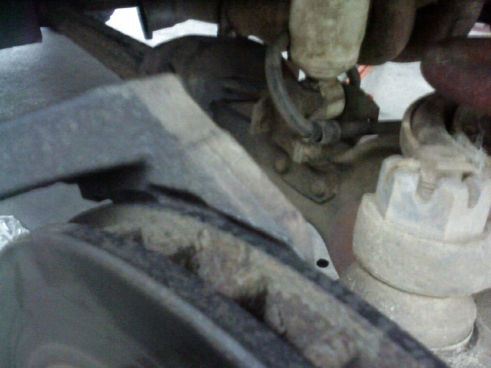 Close-up of rusty suspension parts and a lug nut on a vehicle