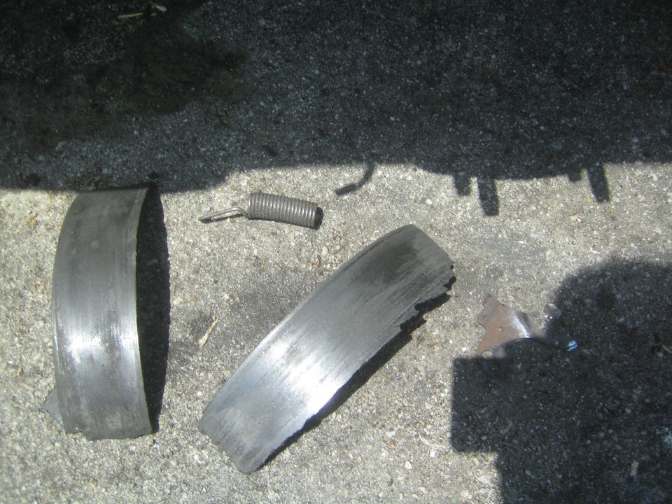 Broken brake drum pieces and a spring on concrete