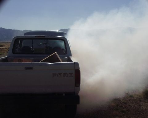 1997 Ford F-250 - A 1997 Ford F-250 truck is seen from the rear, billowing thick white smoke. Another vehicle is partially visible in front.