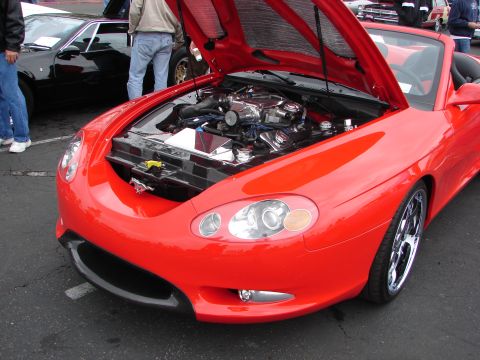 1992 Ford Taurus - A red convertible sports car is parked with its hood open, revealing the engine bay.
