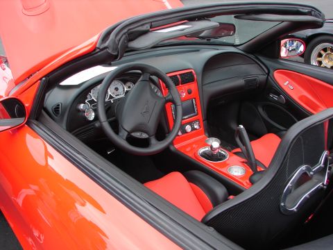 1992 Ford Taurus - Interior of a red convertible, showing dashboard, steering wheel, and seats. Another vehicle is reflected in the side mirror.