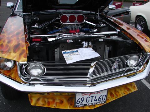 1992 Ford Taurus - A classic 1969 Ford Mustang with custom flame paint and exposed engine is displayed at a car show.